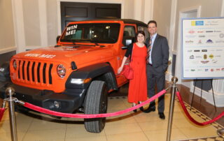 People posing with red Jeep Wrangler for raffle
